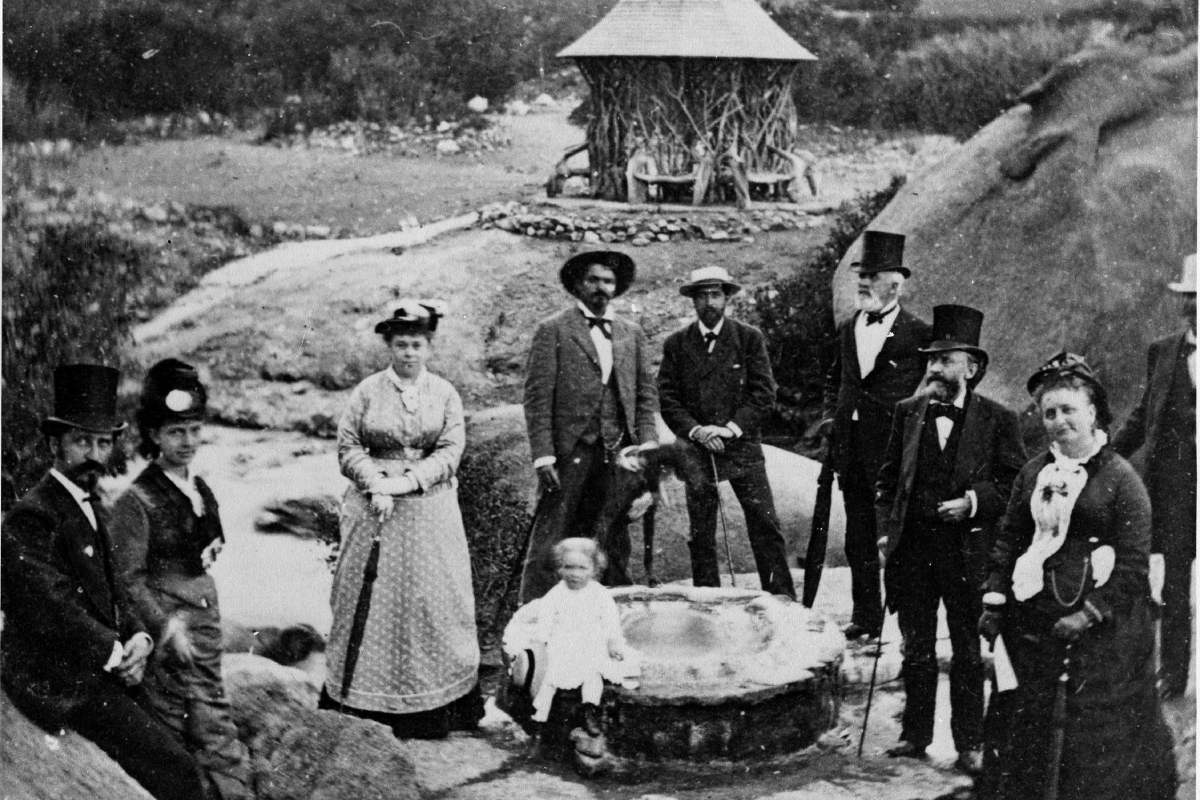 Black and white photo of people in 1870s standing around mineral spring.