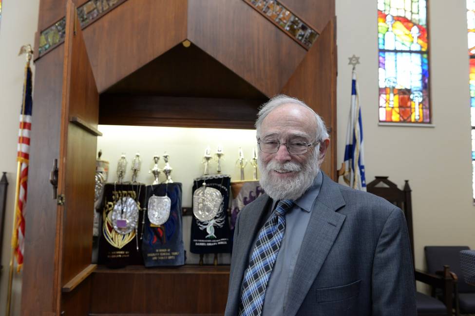 Man in glasses and suit standing inside Jewish temple.