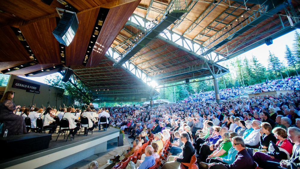 A large audience in an outdoor amphitheater watching the Dallas Theater perform during Bravo! Vail summer music festival.