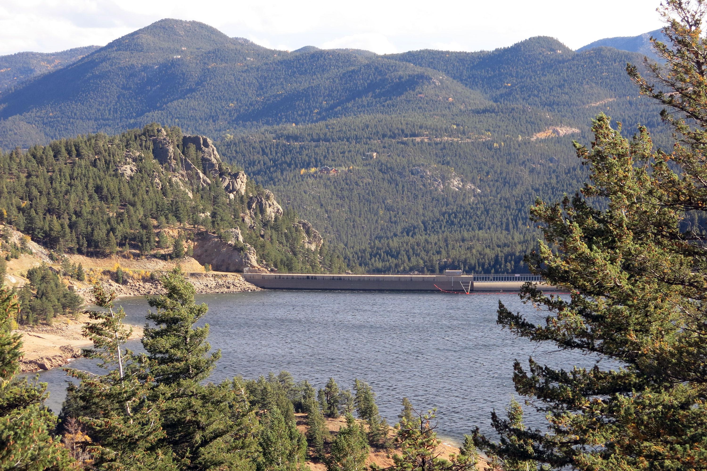 A panoramic view of Gross Reservoir, surrounded by evergreen tree-filled mountains.