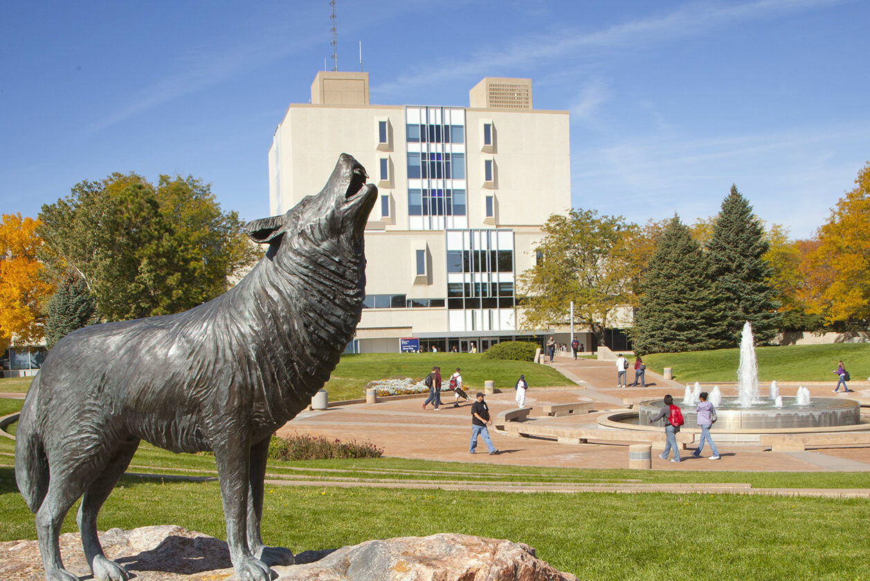 wolf statue in foreground of campus buildings