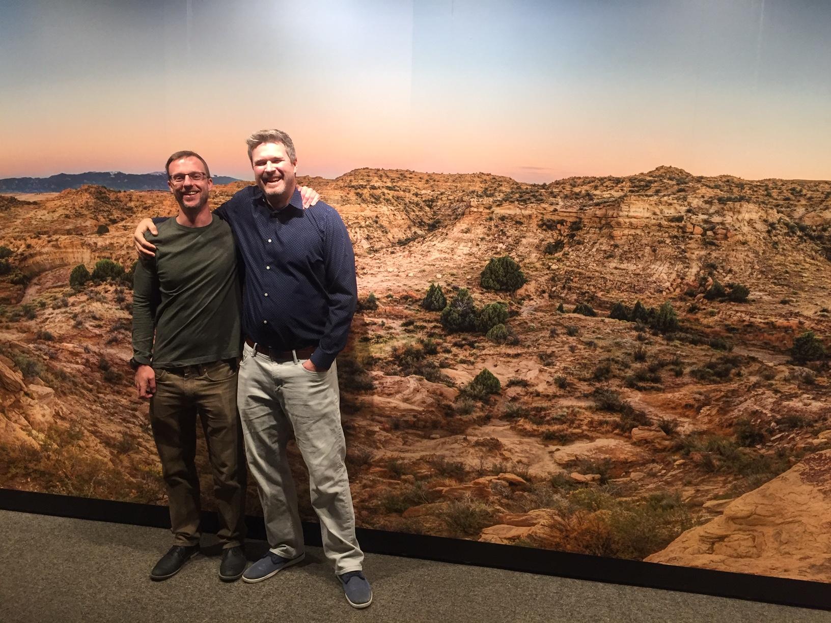 Tyler Lyson and Ian Miller in front of landscape of Corral Bluffs at exhibit at Denver Museum of Nature and Science