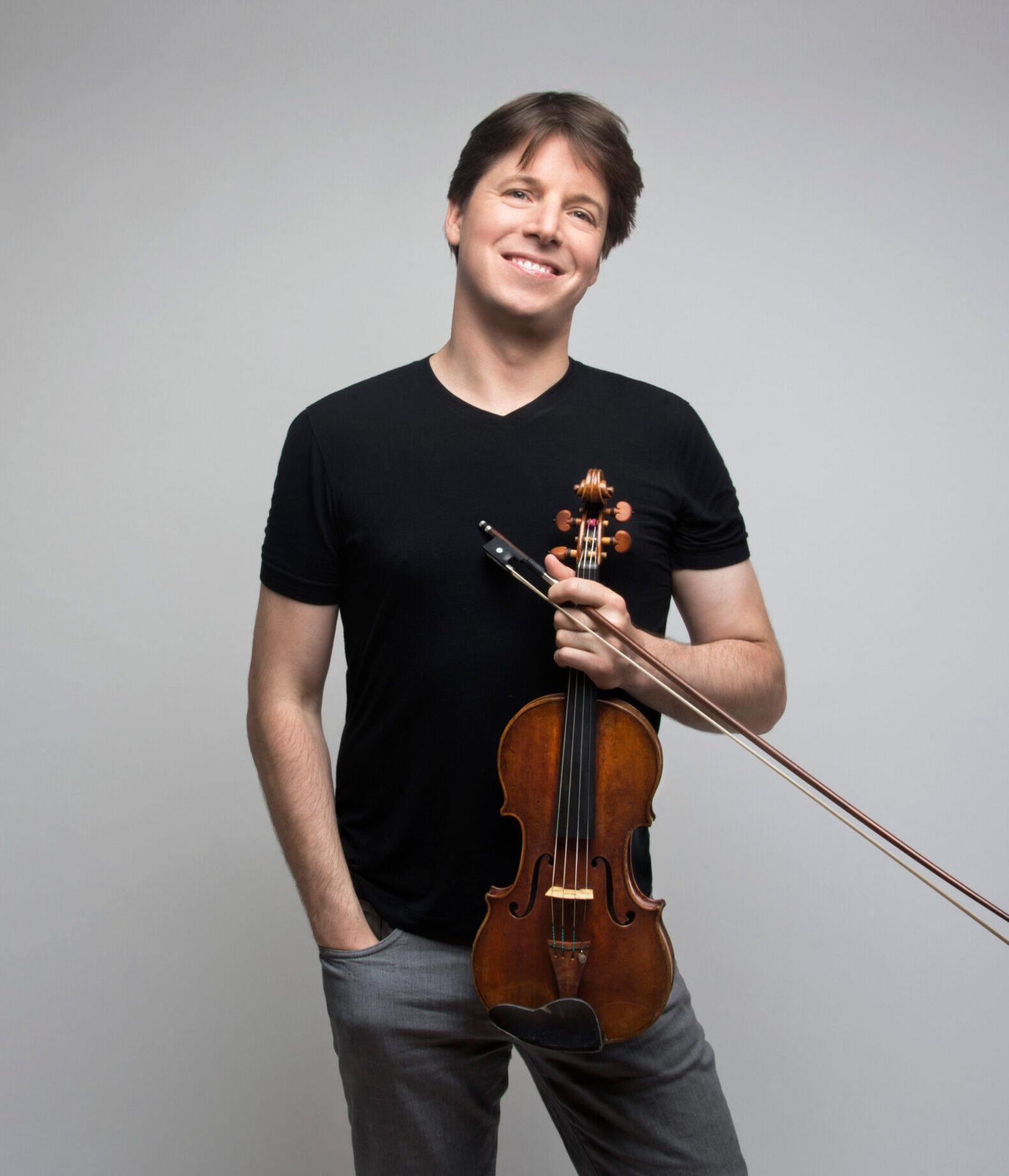 Violinist Joshua Bell standing holding his violin