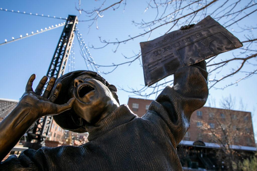 A bronze statue of a boy holding a newspaper up stands in Golden, Colorado.