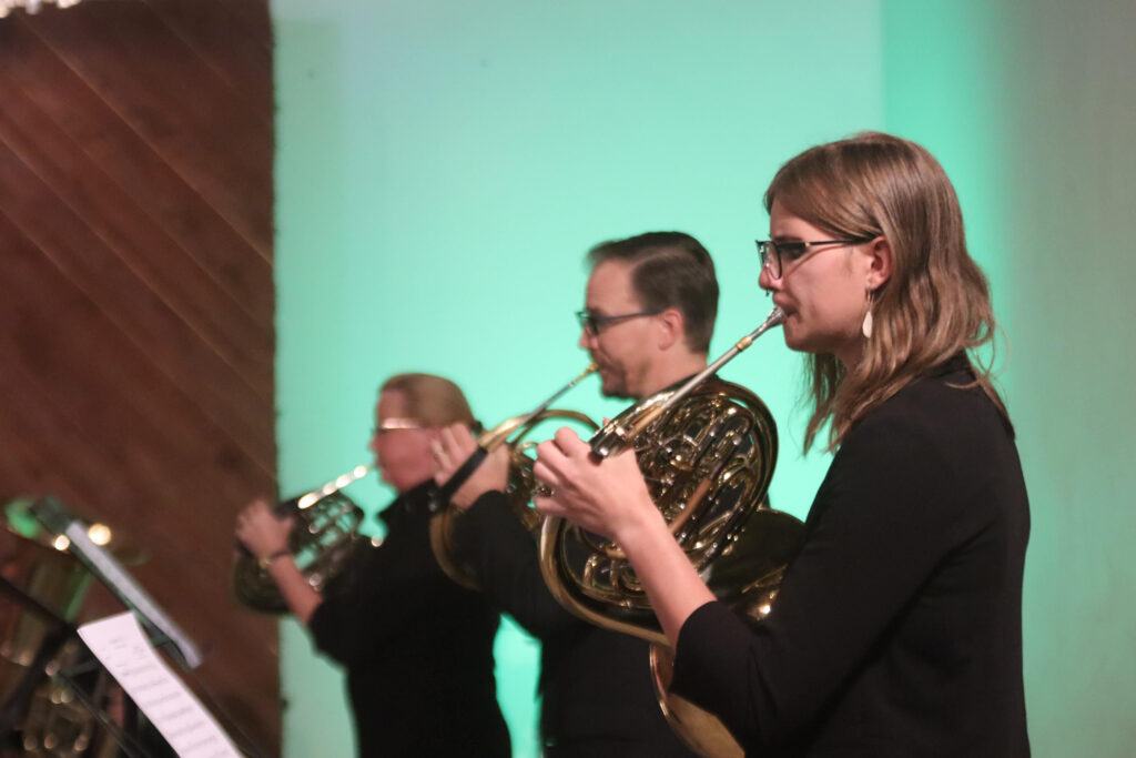 Three musicians with brass instruments facing left