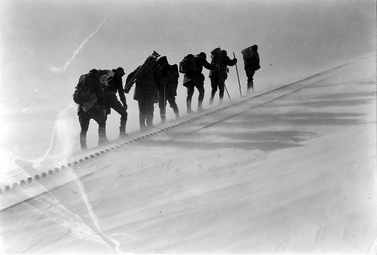 An archival photo shows the AdAmAn Club hiking in difficult conditions.