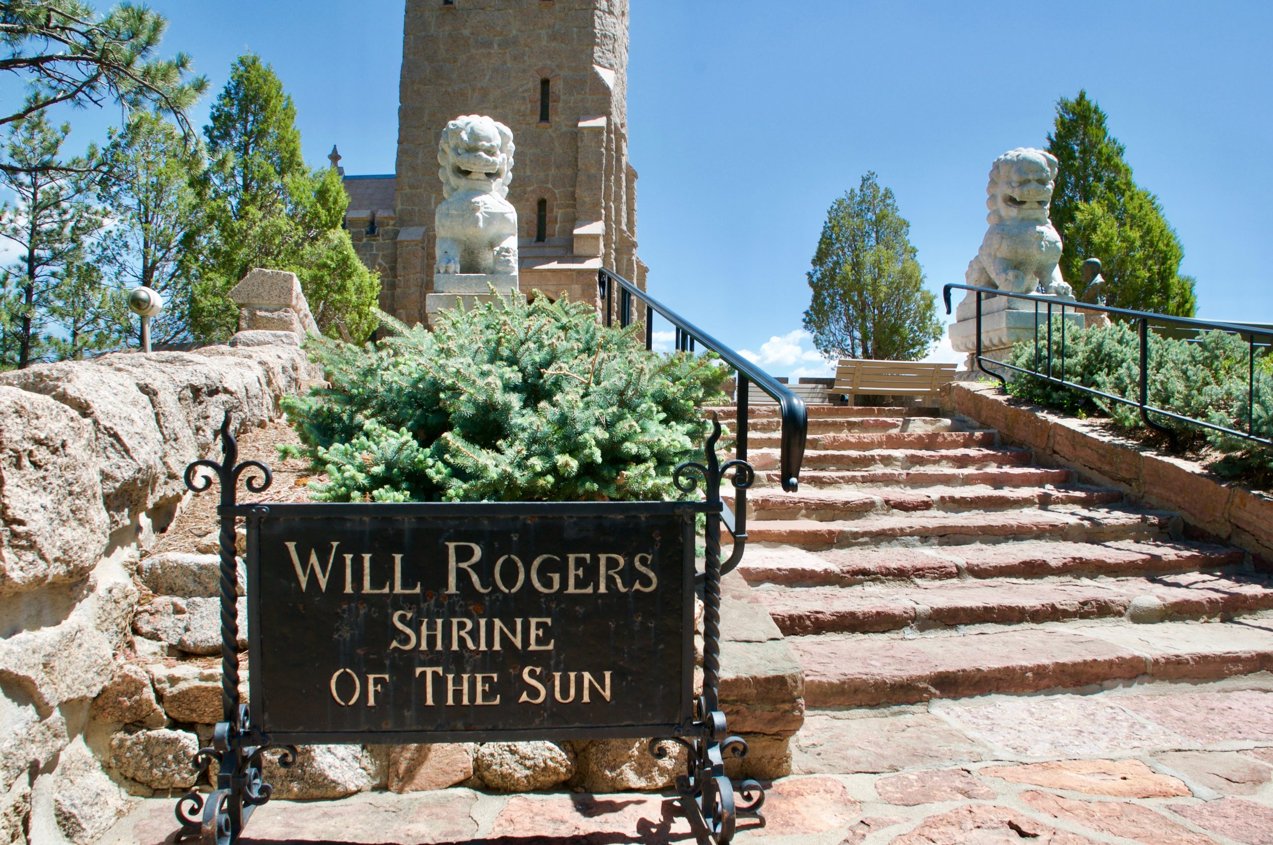 A sign reading "Will Rogers Shrine of the Sun" in front of stone steps.