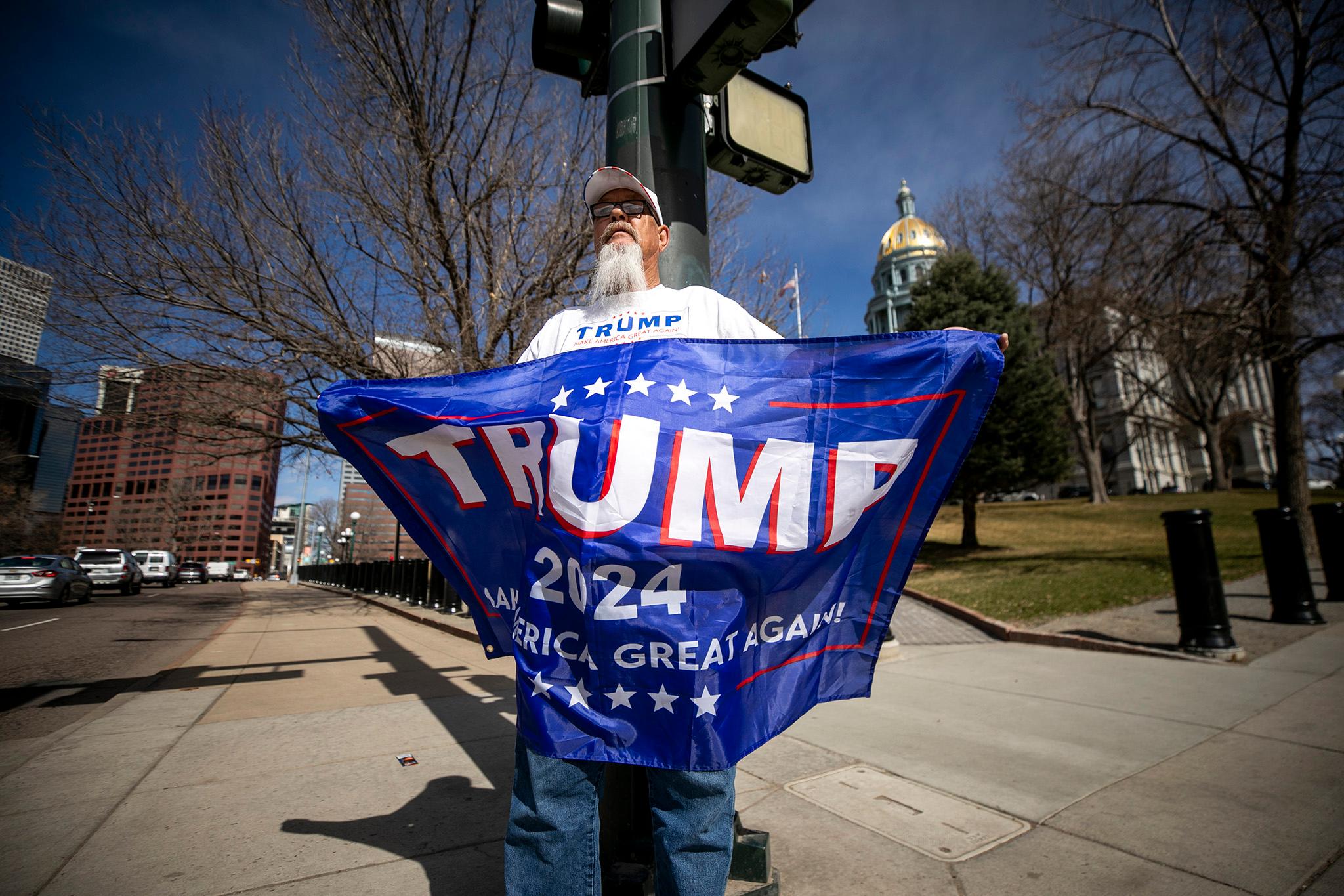 Larry Woodall holds a Trump campaign flag