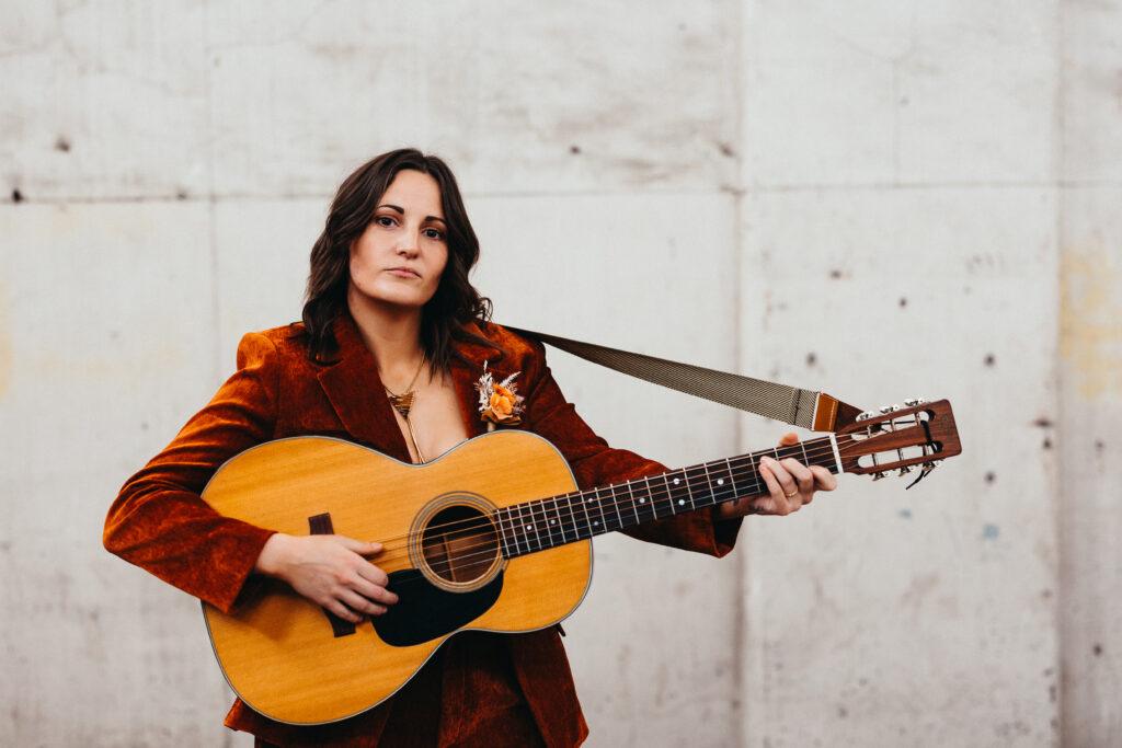 Musician Amy Martin poses with acoustic guitar.