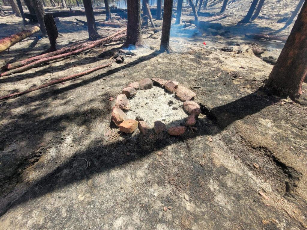 A picture of a campfire ring in a forest investigators say sparked a wildfire.