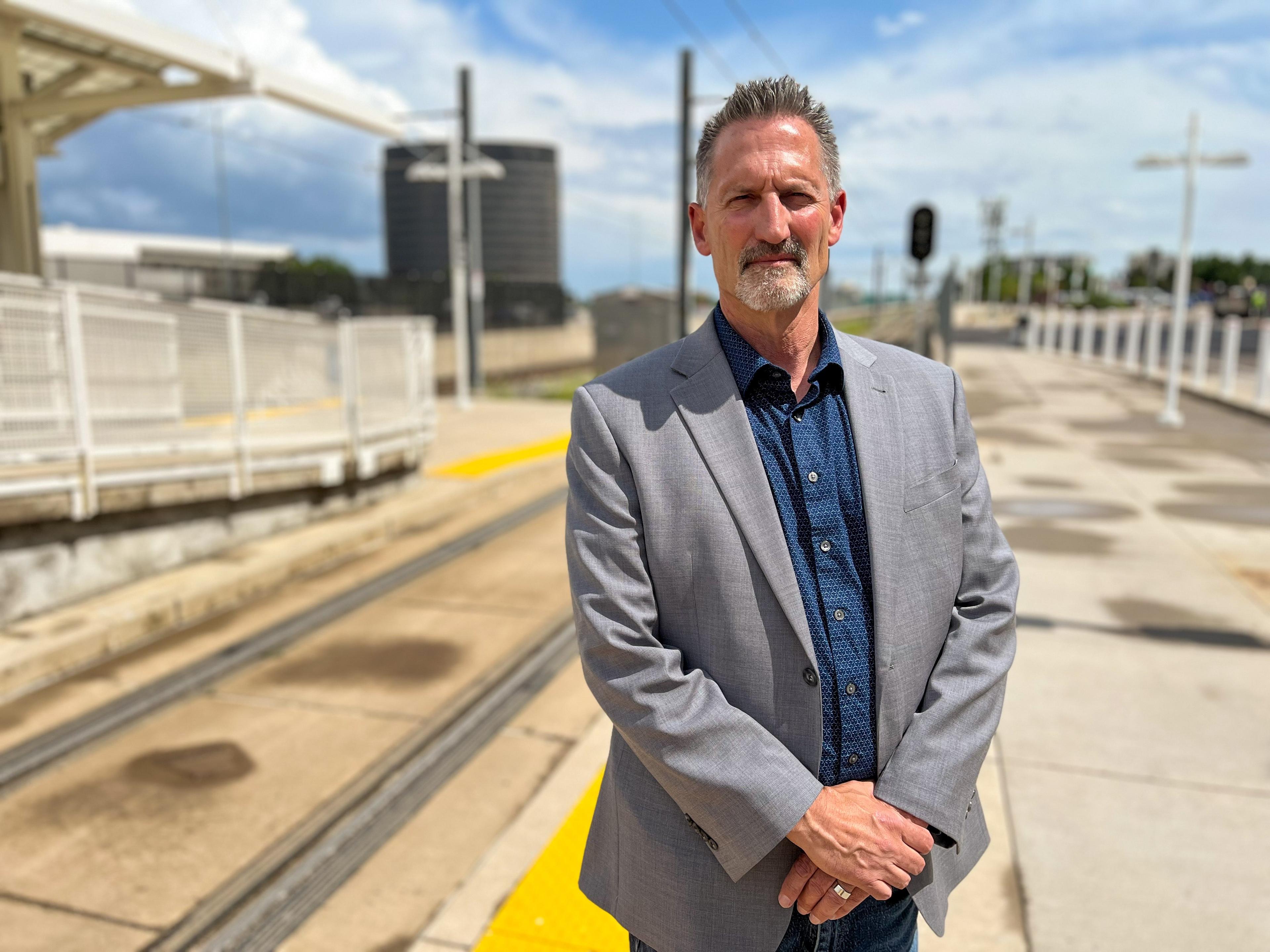 A transit official standing for a portrait at a light rail station in Denver