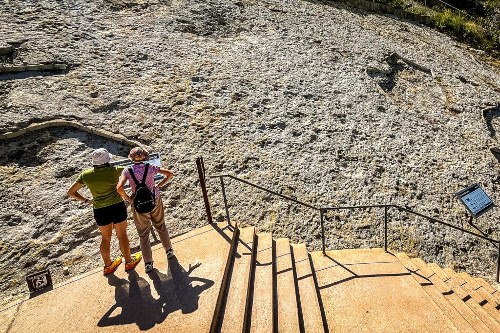 Dinosaur Ridge visitors look at ancient footprints in rock