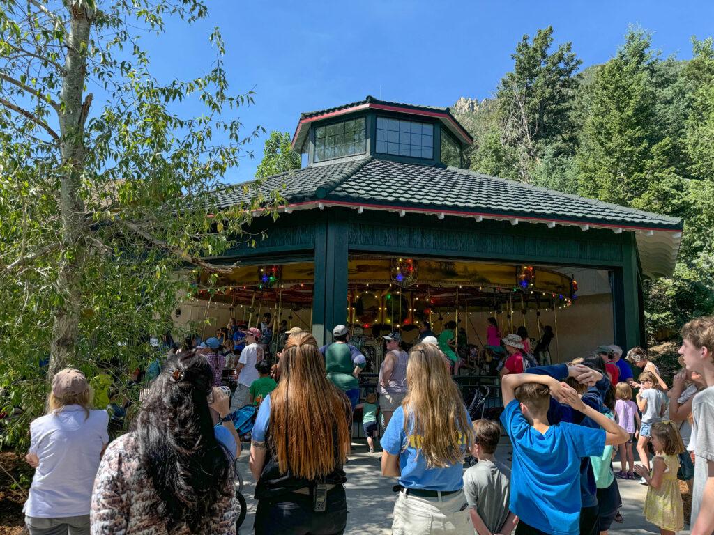 Crowd of people staring at a carousel at the Cheyenne Mountain Zoo