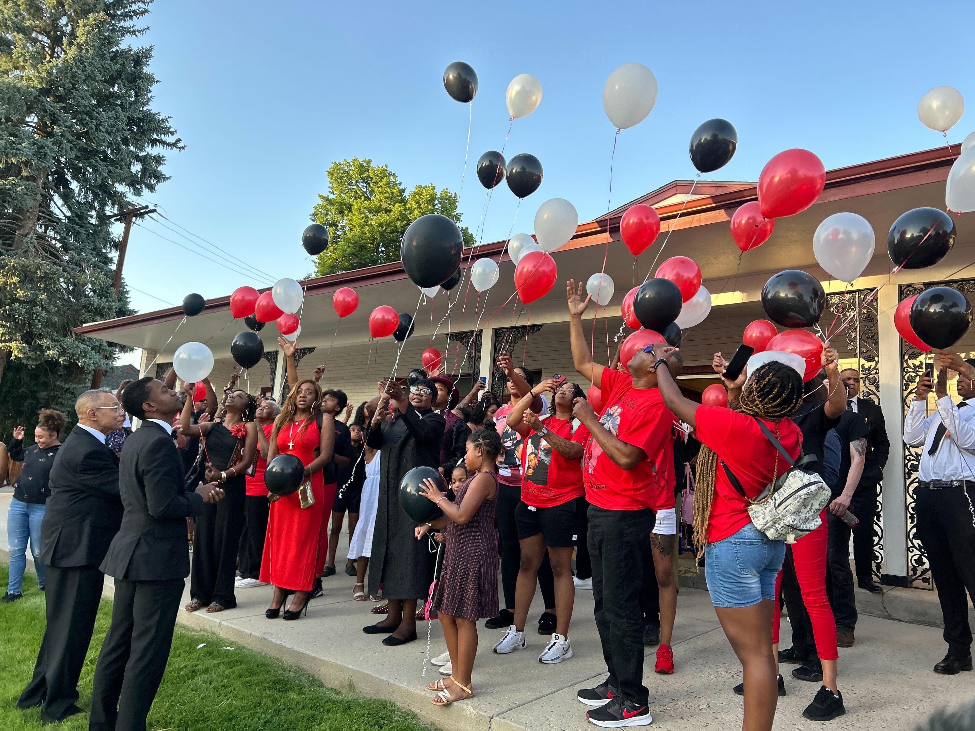 Family and friends release red, black, and white balloons in the air in memory of Kilyn Lewis, who recently died after being shot and killed by officers last month.