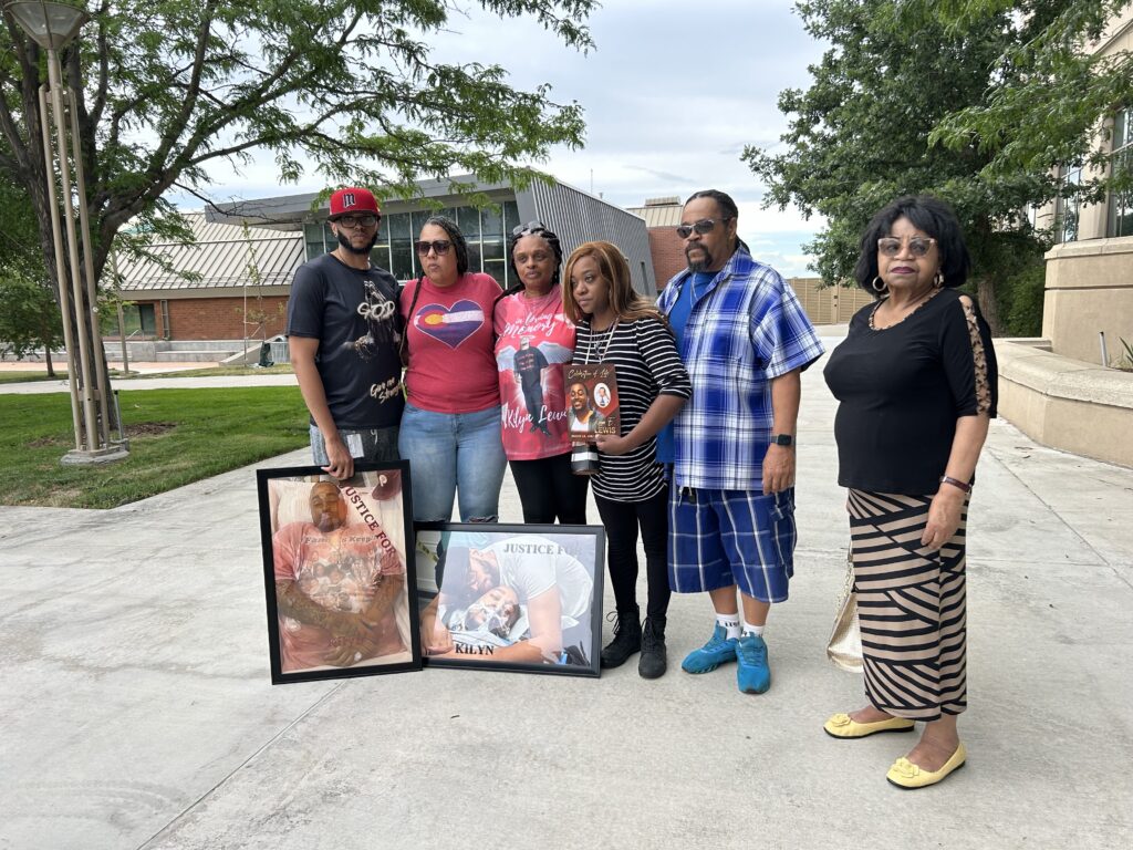 Several people pose with pictures of a loved one who was shot and killed by police near a government building.