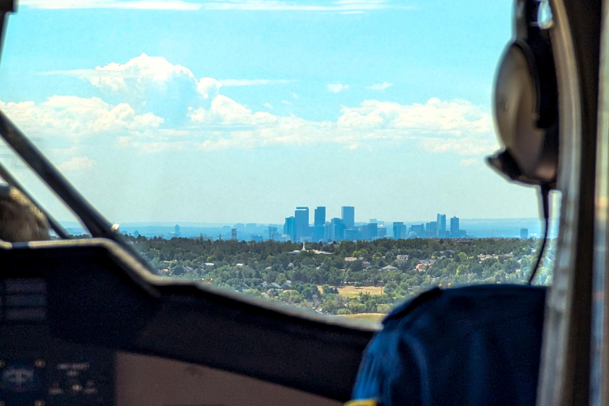 A view of downtown Denver from the cockpit inside a plane.