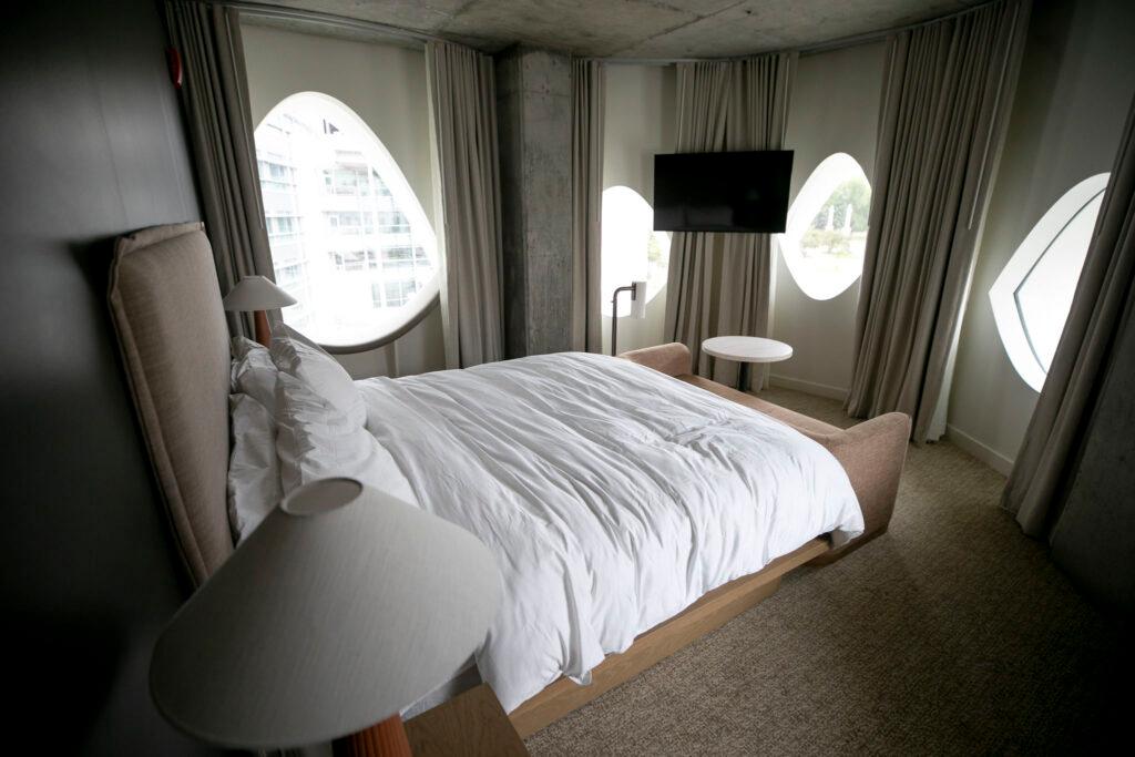 A bed in a round-shaped room lined with eyeball-shaped windows.