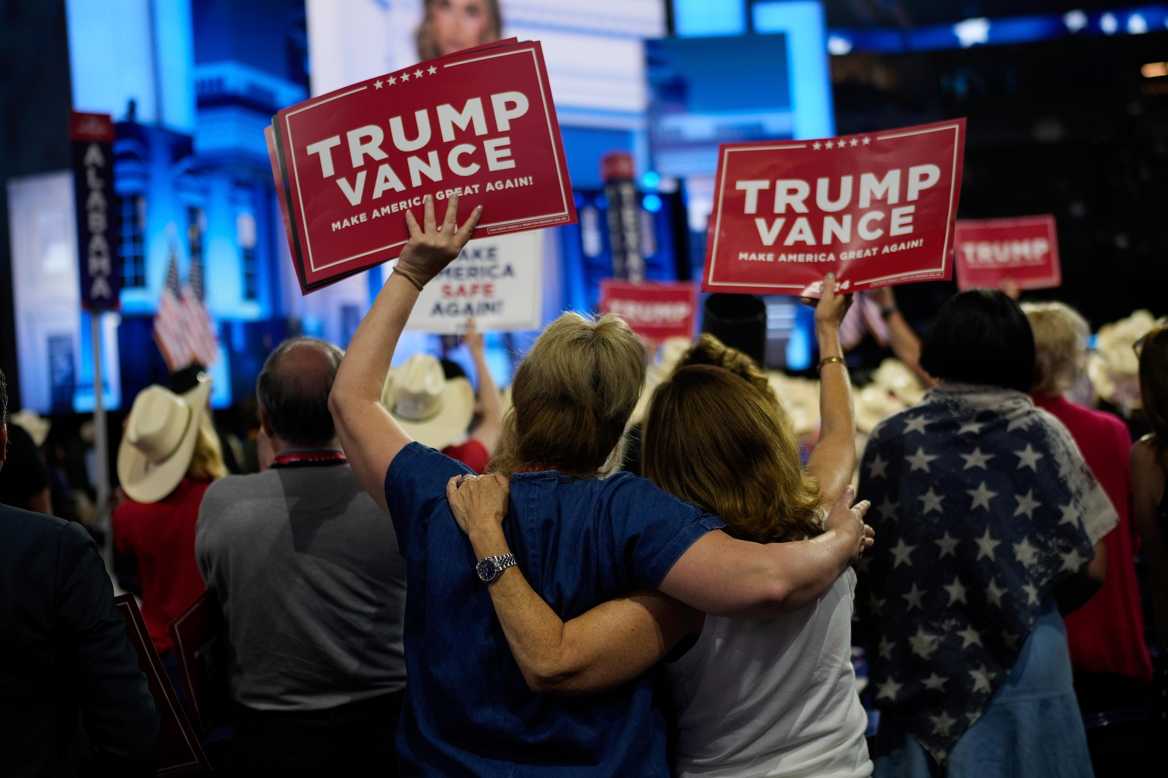 A crowd of people facing away from the camera with a few holding up TRUMP VANCE signs.