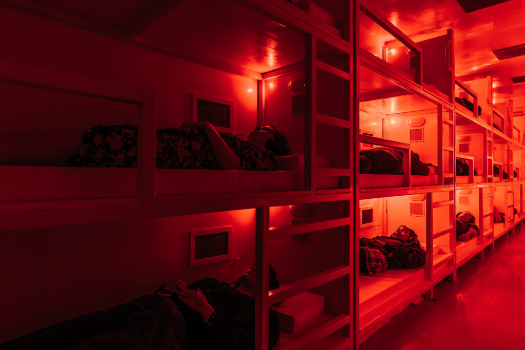 Audience members lying in bunks with headphones on at Darkfield's immersive &quot;Coma&quot; exhibit.