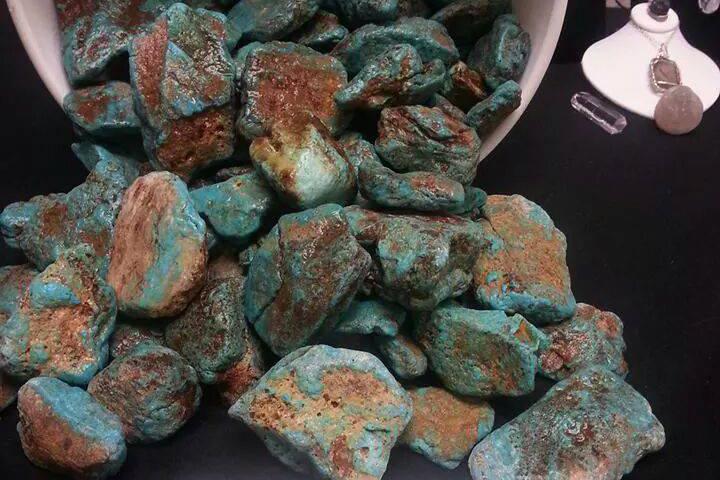 Irregularly shaped chunks of turquoise spill from a container on a display table.