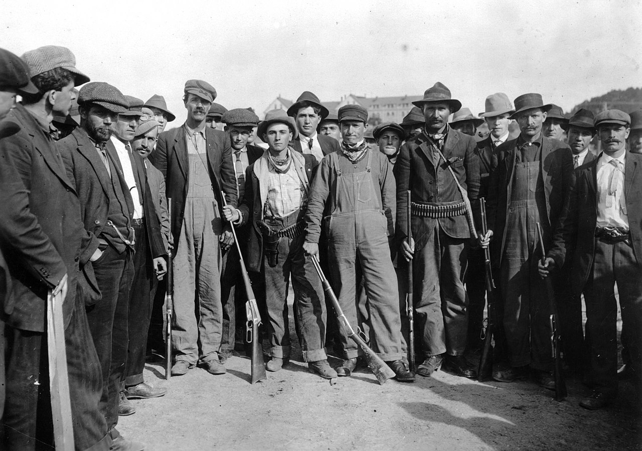 A black and white photo of a group of men standing with rifles.
