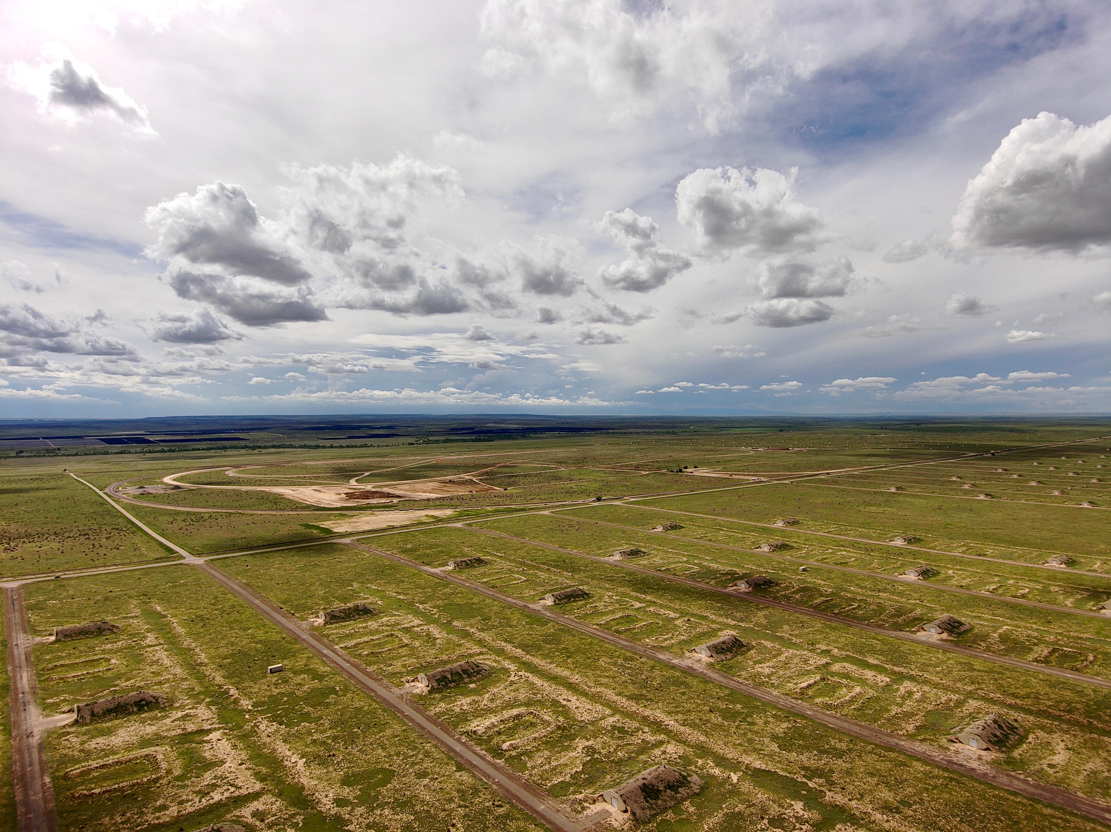 An aerial view of lines of rectangular bunker structures with rounded rooflines that appear to be old. There also appears to be foundations or something similar in between some of the bunkers as if buildings might have been removed.