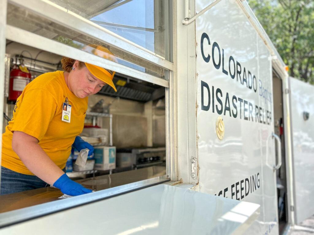 A volunteer in a yellow shirt is scrubbing a counter in a disaster response food truck.