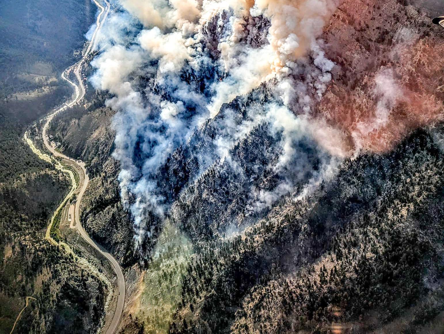 An aerial photo of a smoky wildfire covering a mountainside.