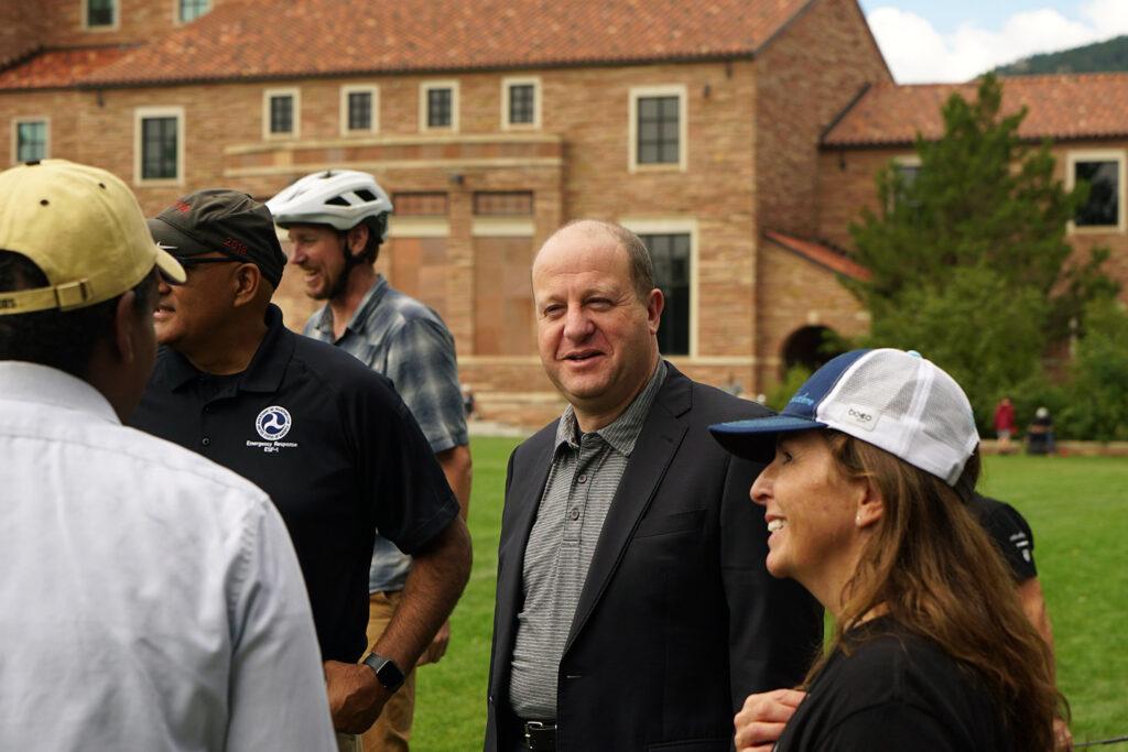 Governor Jared Polis stands in a group of people.