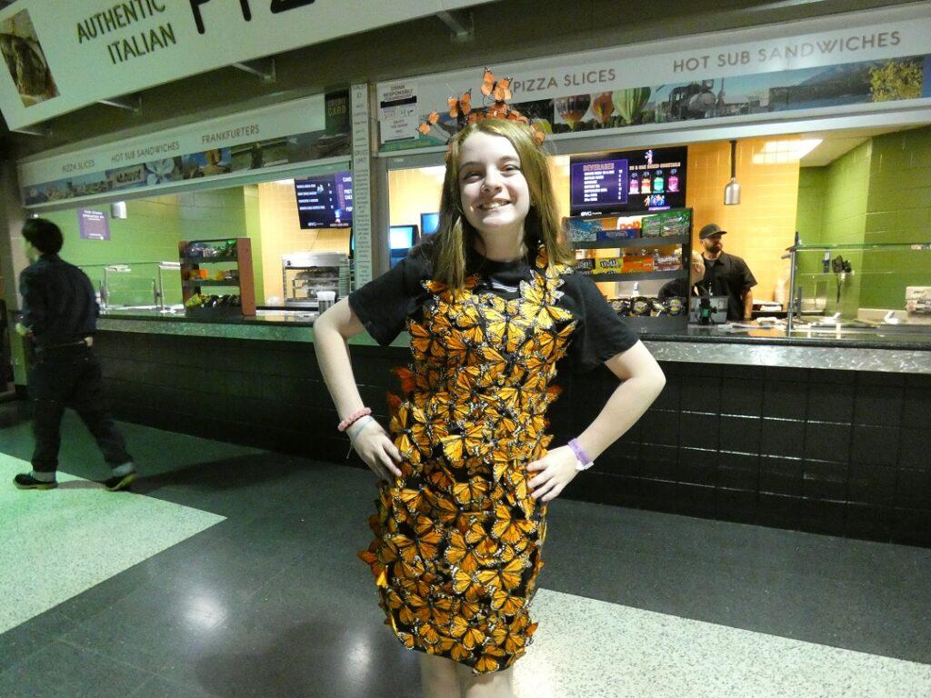 A girl wears a dress made out of butterflies