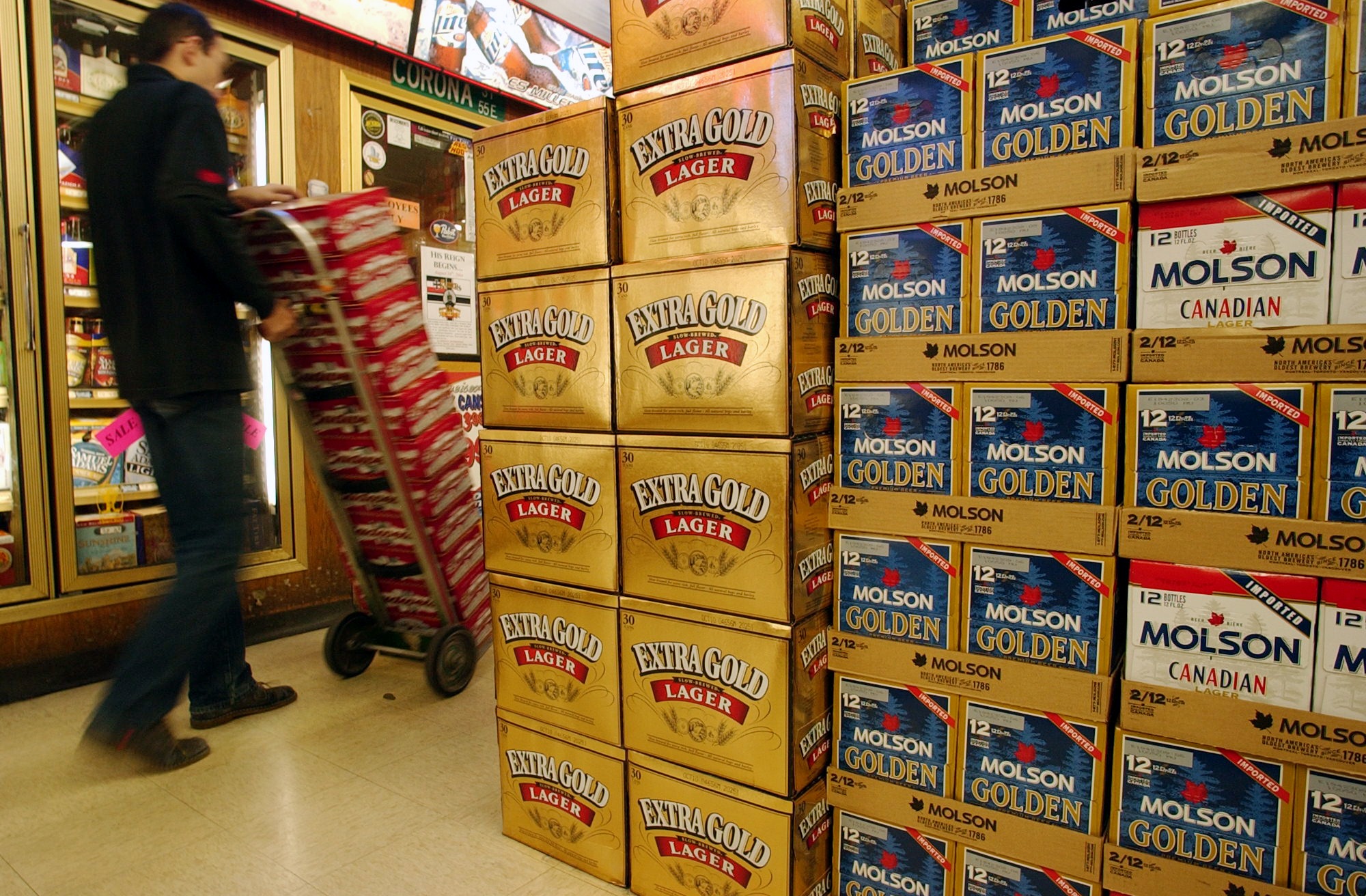 An Argonaut Liquors employee carts beer by a display of Extra Gold Lager