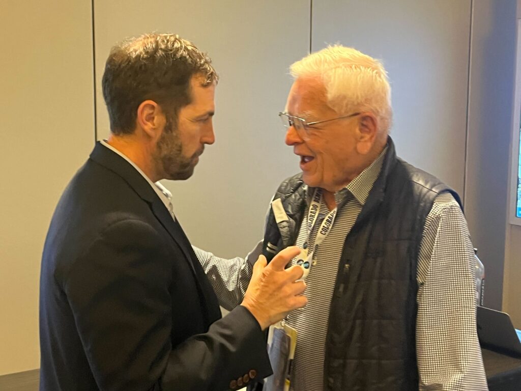 Rep. Jason Crow and former Gov. Roy Romer stand in close conversation at the 2024 Democratic National Convention.