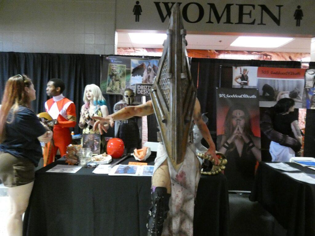 A woman in a costume with a large pyramid head poses for a photo.