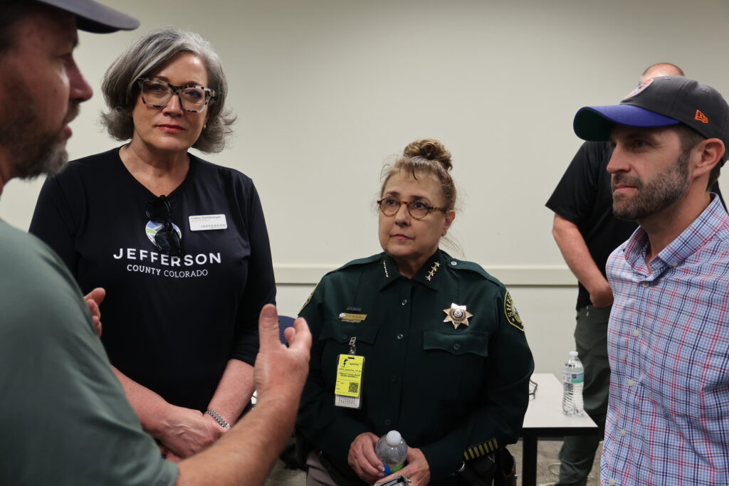 Democratic Representative Jason Crow, Sherriff Reggie Marinelli, and Jefferson County Commissioner Lesley Dahlkemper listen to a briefing about the Quarry Fire.