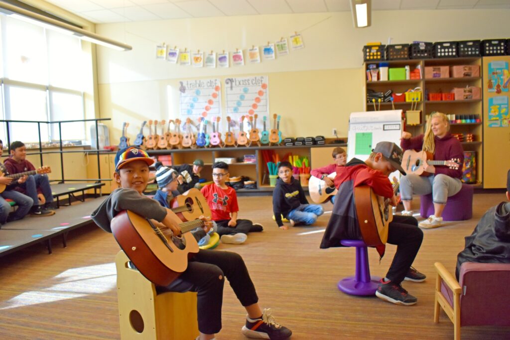 Students play guitar in school.