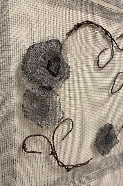 Poppy flowers made of layers of screen with barbed wire stems on a hardware cloth background