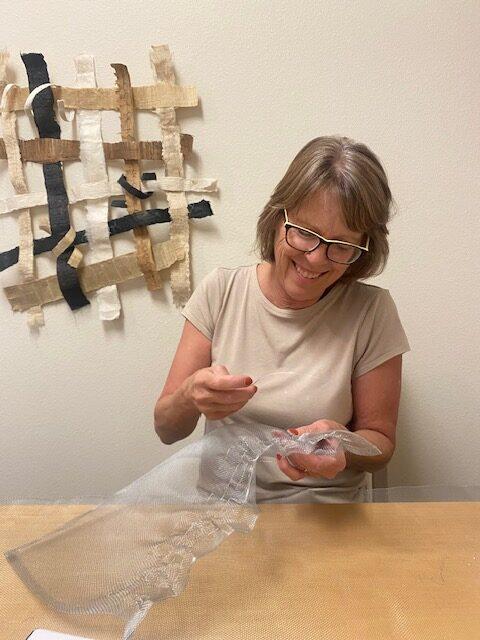 a woman stitches a piece of metal screening