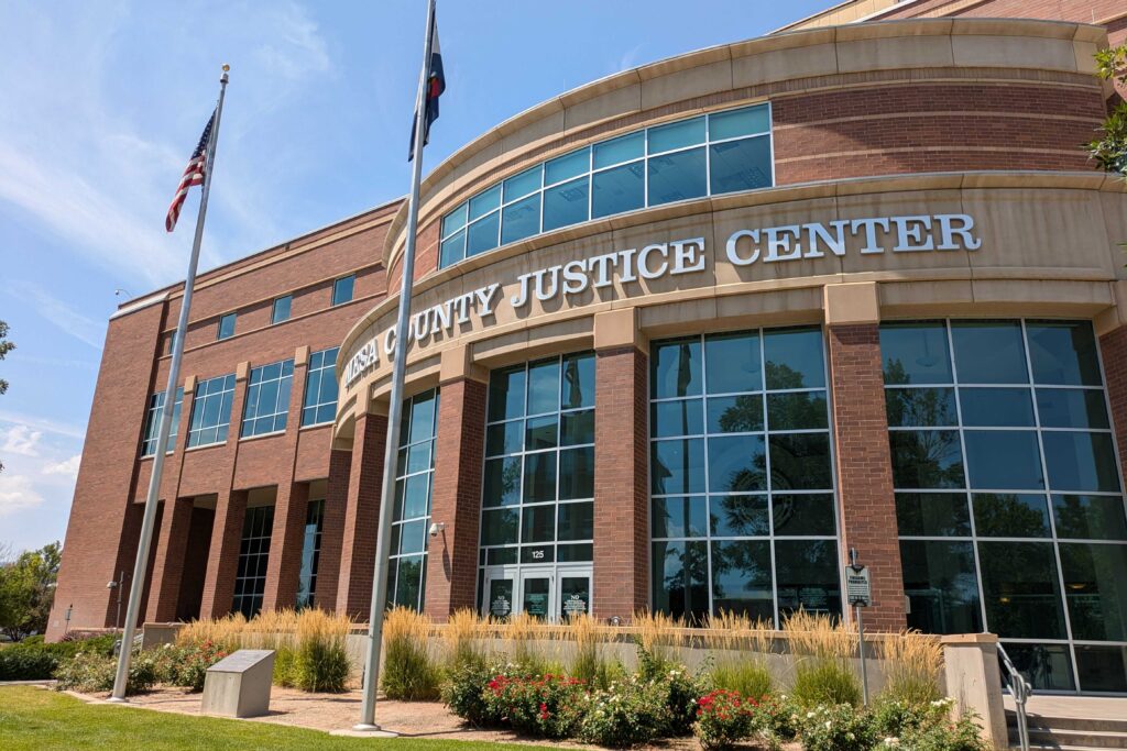 An exterior shot of a courthouse with the Colorado and USA flags in front.