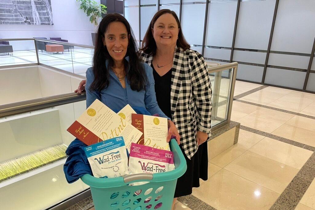 Cyndi Bray of Denver holds a basket of her invention, Wad-Free along with her patents. She is standing next to Molly Kocialski, Rocky Mountain regional director of the United States Patent and Trademark Office., in the lobby of the CPR News building.