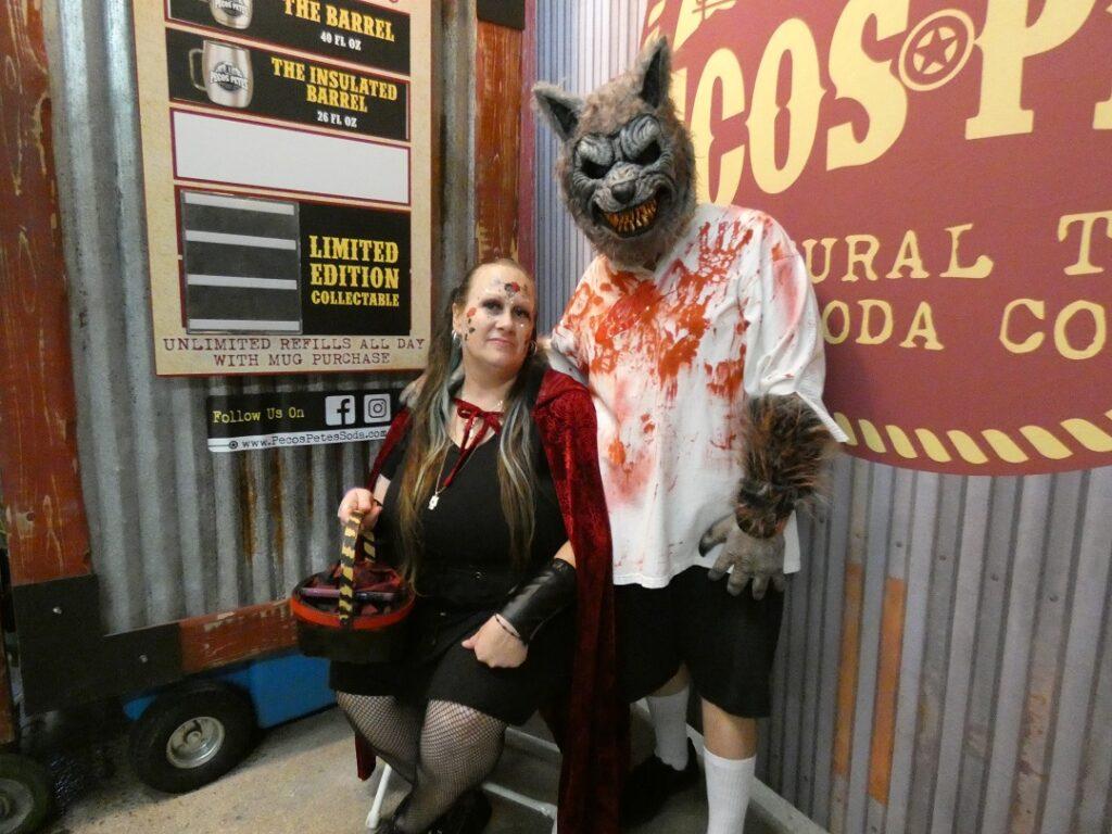 A man in a wolf costume poses with a woman dressed as Little Red Riding Hood.