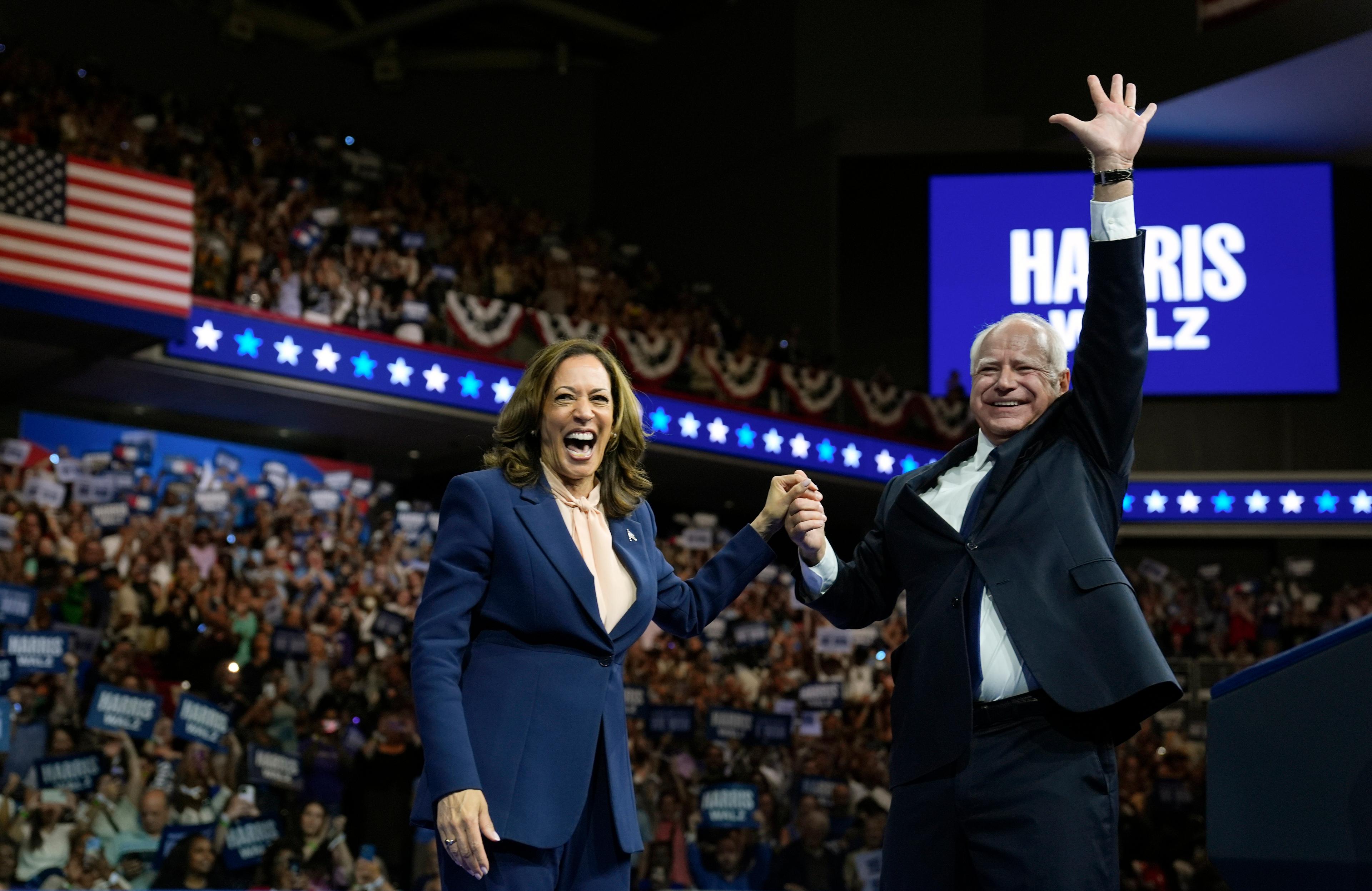 The 2024 Democratic presidential ticket, Kamala Harris and Tim Walz, raise their arms at a campaign rally in Philadelphia, PA.