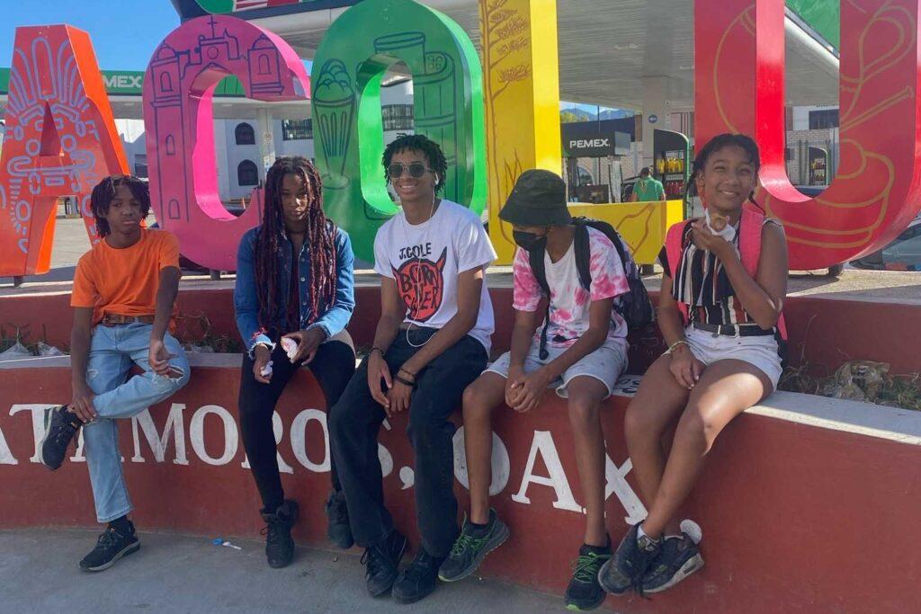 The four Wells family children and their cousin pose outside a sign in a community in Mexico.