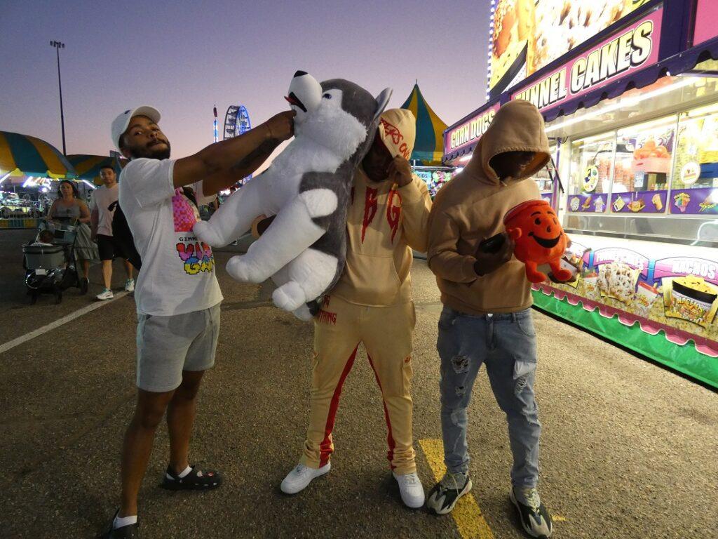 three men pose with a stuffed animals outside