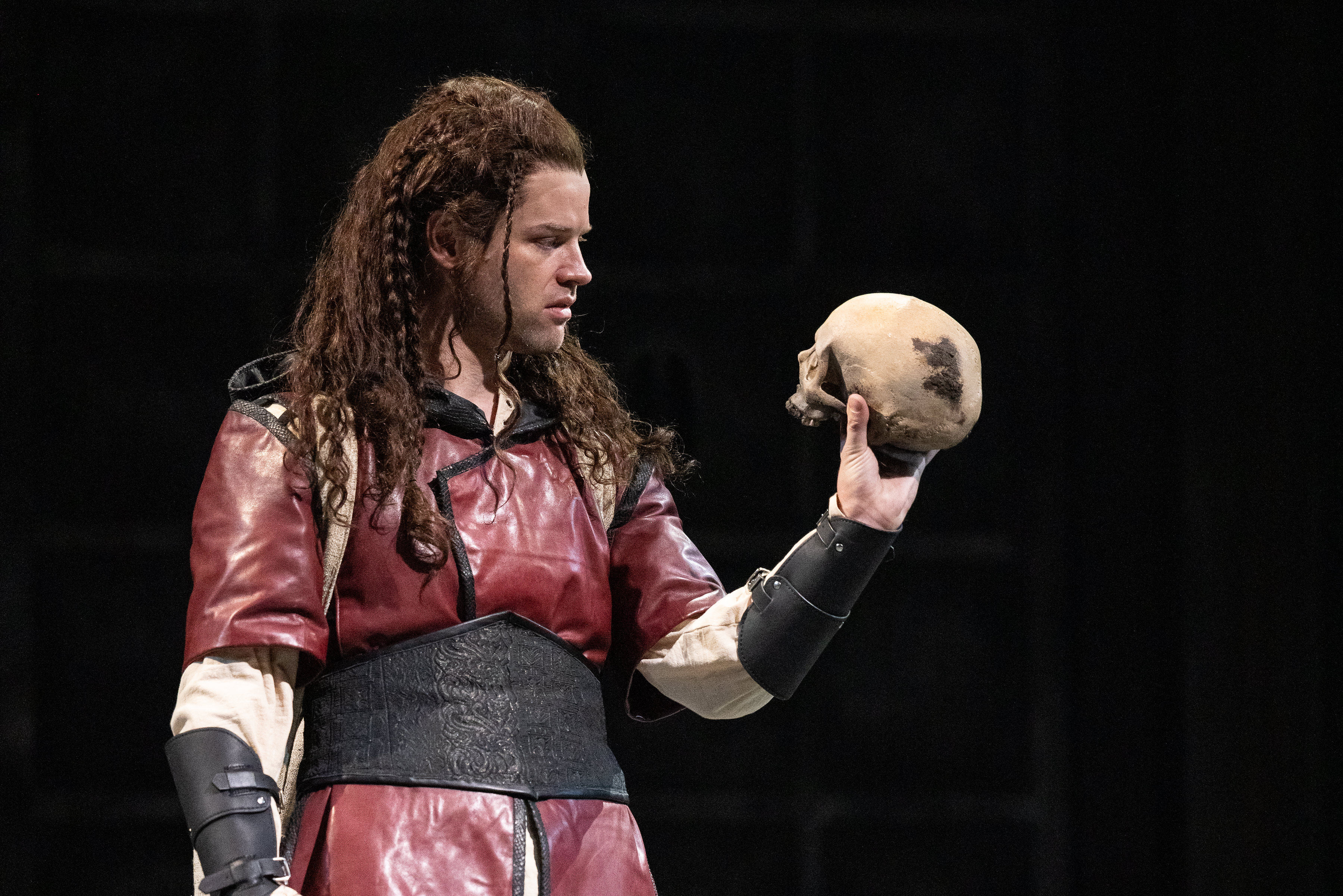 Actor Ty Fanning holds a skull in a scene from the Denver Center Theatre Company's 2024 production of Hamlet.