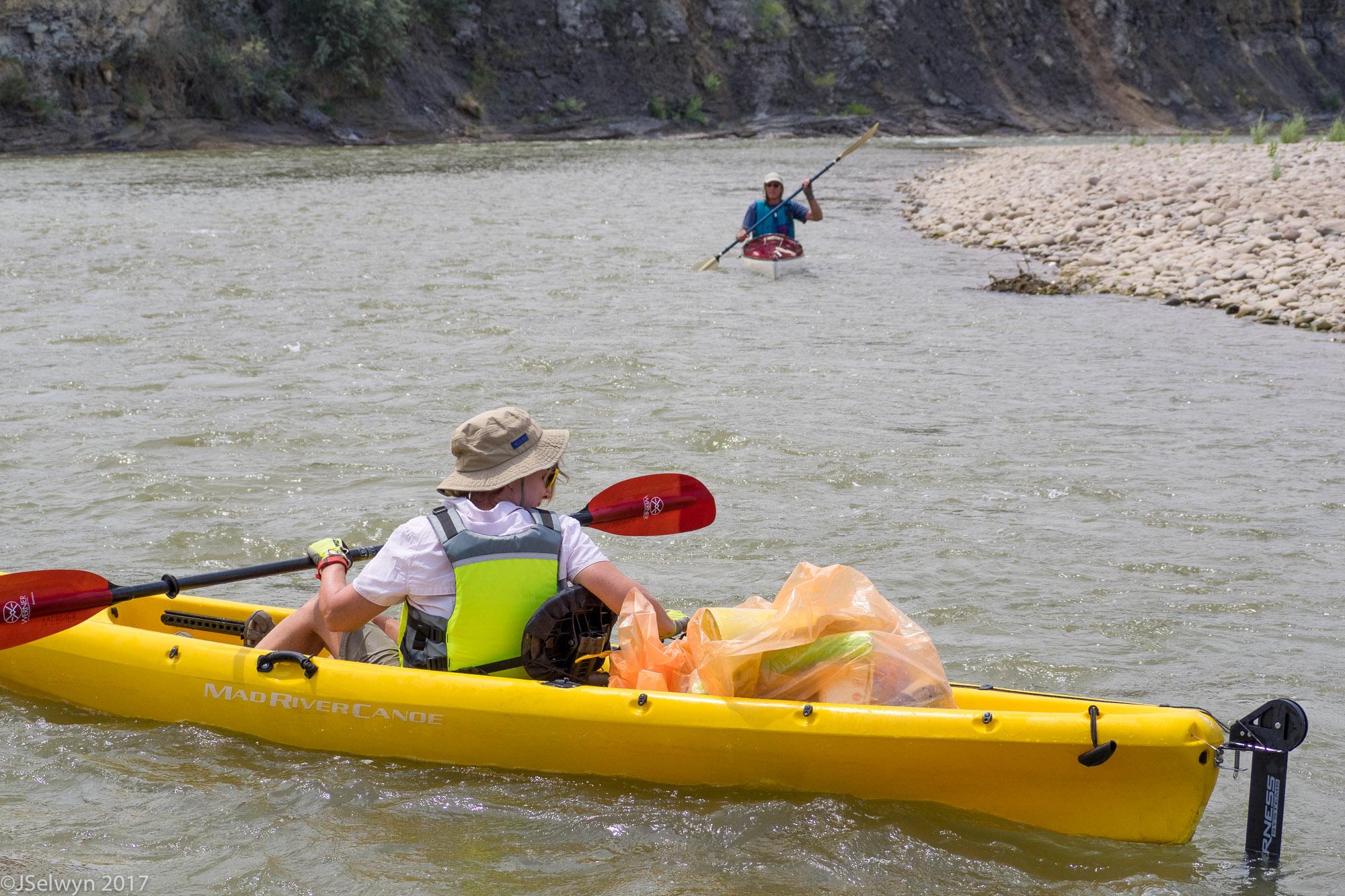 Volunteers in kayaks on a river loaded with trash found in the Colorado River.