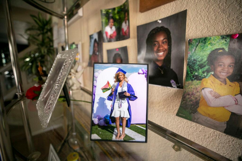 A photo of a woman in a blue graduation gown, holding a red, yellow and green flag, sits on a shelf along with other images.