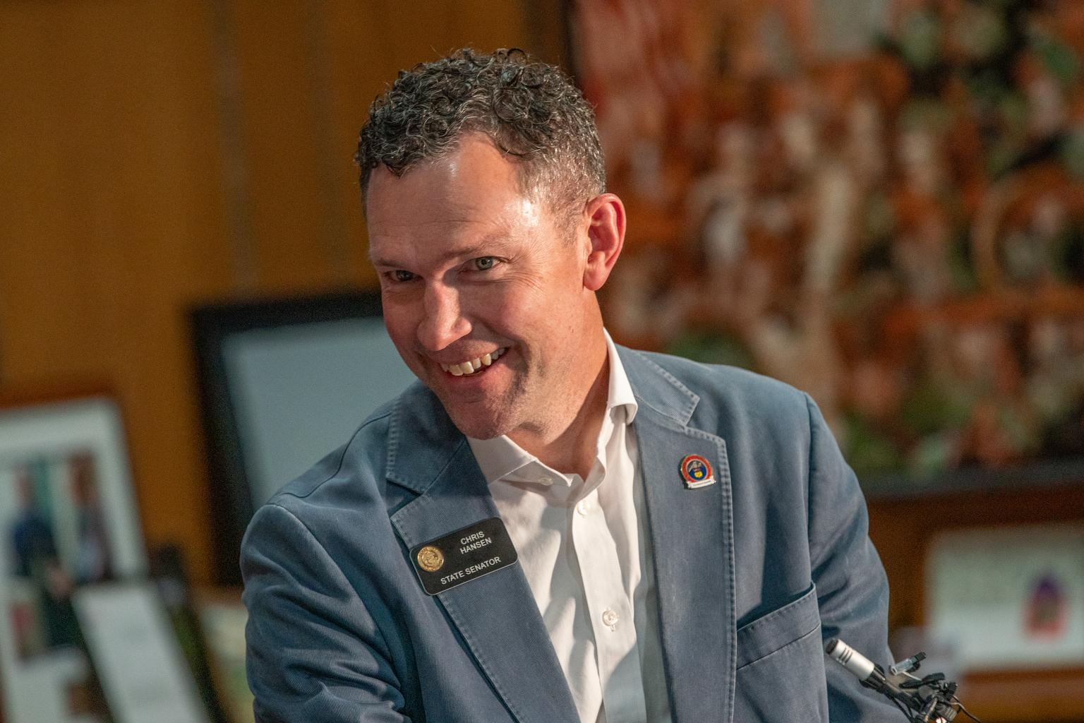 State Sen. Chris Hansen smiles after he watches Governor Jared Polis sign a property tax relief bill