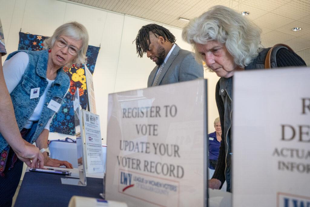 New US citizen Peter-John Rowe, center, of Jamaica, registers to vote