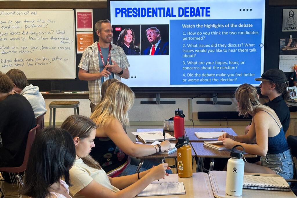 A teacher talks with students in class.