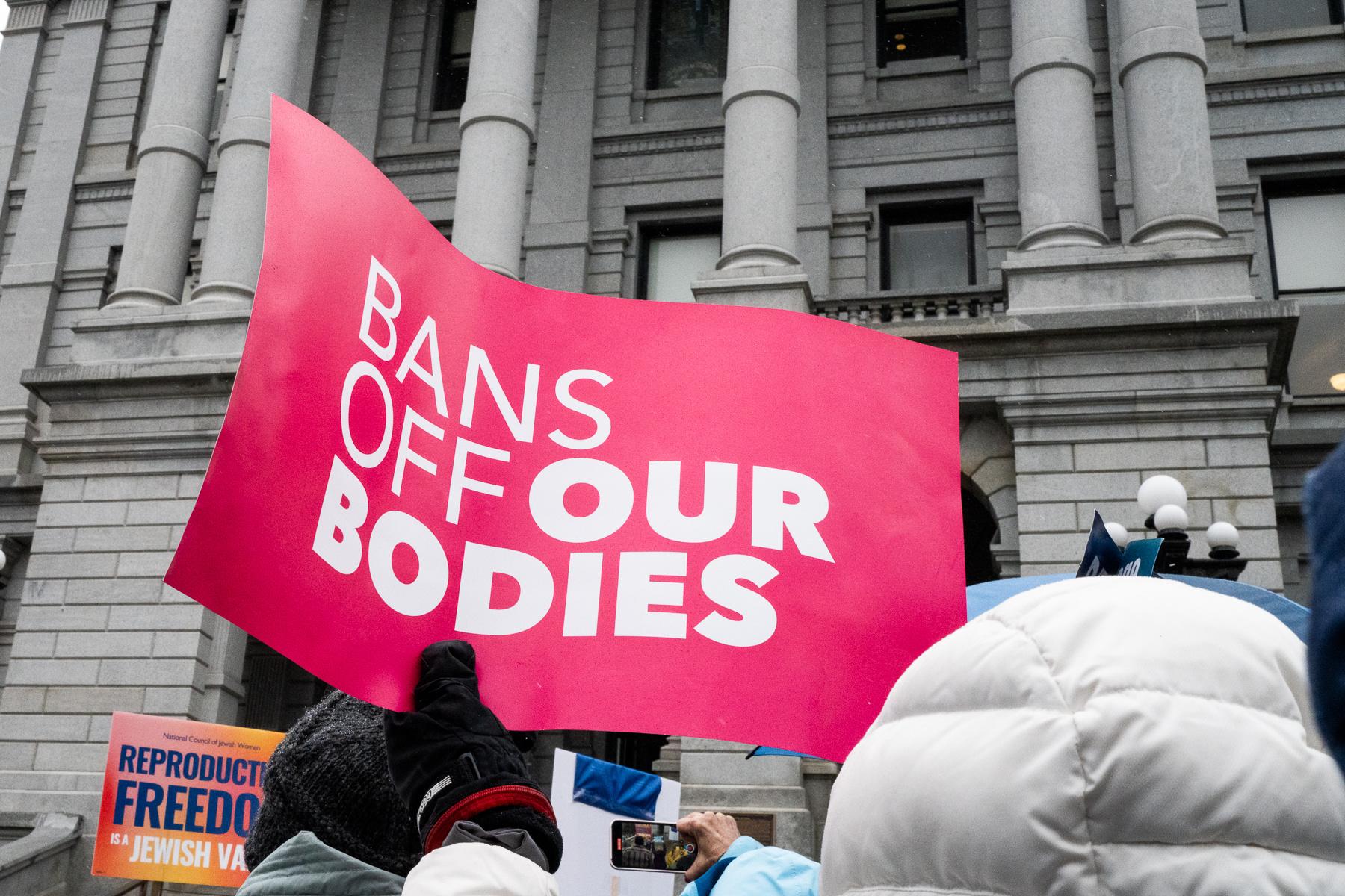 An abortion rights supporter holds a sign saying “Bans off our bodies"